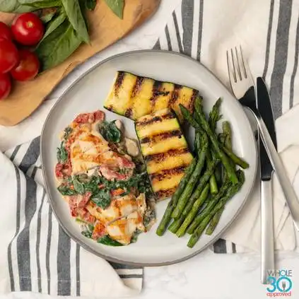 Pasture-raised grilled chicken with creamy tuscan sauce and grilled zucchini and asparagus