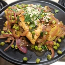 Marley Spoon chicken Vesuvio over roasted potatoes with peas, red onion, parsley and grated parmesan on a black plate