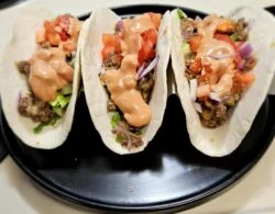 Three Marley Spoon deluxe cheeseburger tacos with ground beef, diced tomato, red onion and burger sauce in flour tortillas
