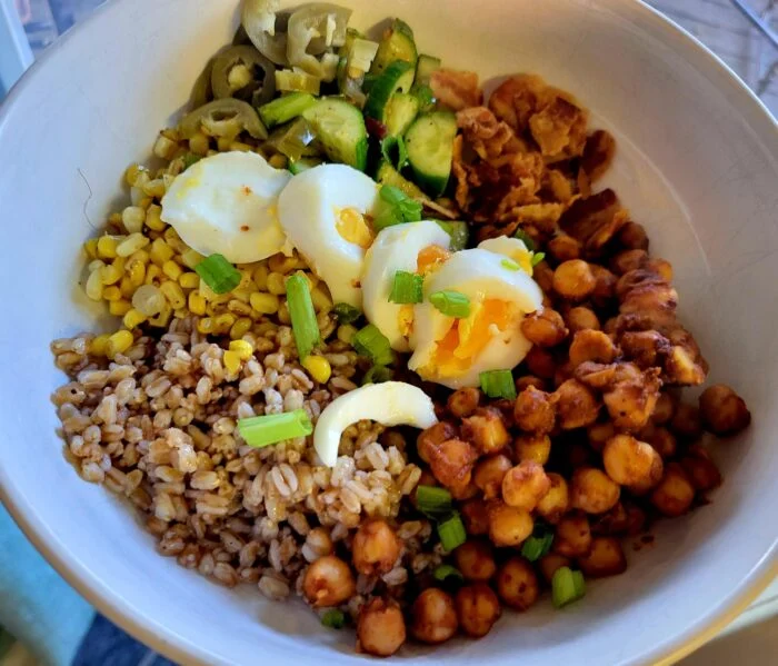 Blue Apron BBQ chickpea and corn grain bowl with farro, hard boiled eggs, cucumbers, jalapenos and scallions in a white bowl