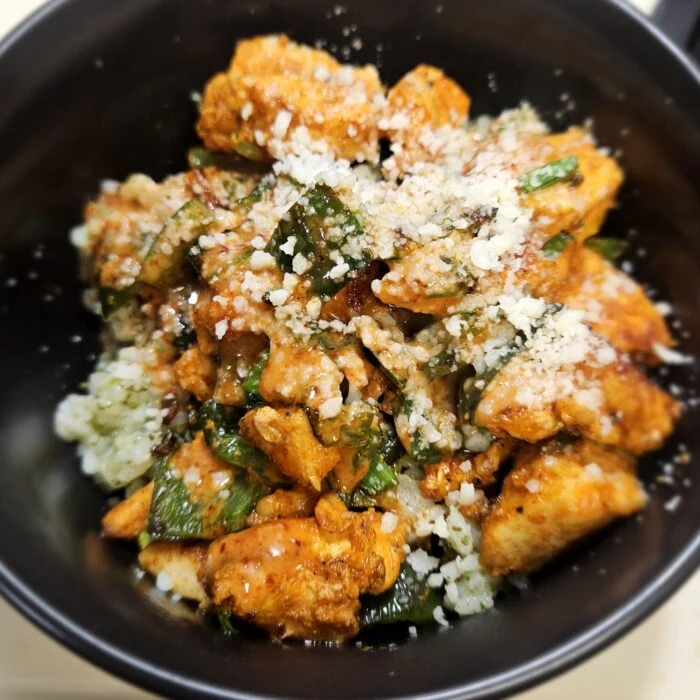 Blue Apron chipotle chicken with poblano peppers and grated cheese over cilantro rice in a black bowl
