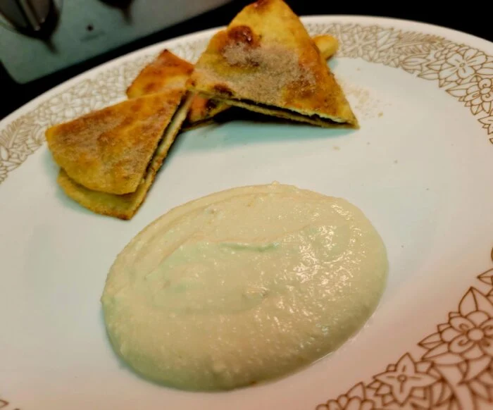 Blue Apron chocolate quesadilla wedges dusted with cinnamon sugar beside a scoop of cannoli cream on a floral rimmed plate