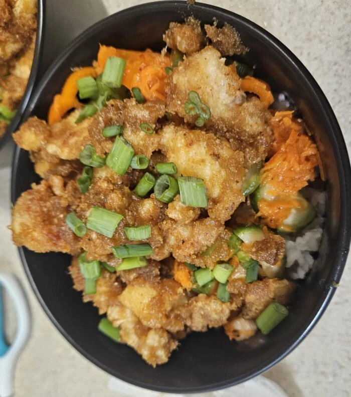 Blue Apron curry peanut chicken, crispy pieces with scallions, carrots and marinated veggies over rice in a bowl