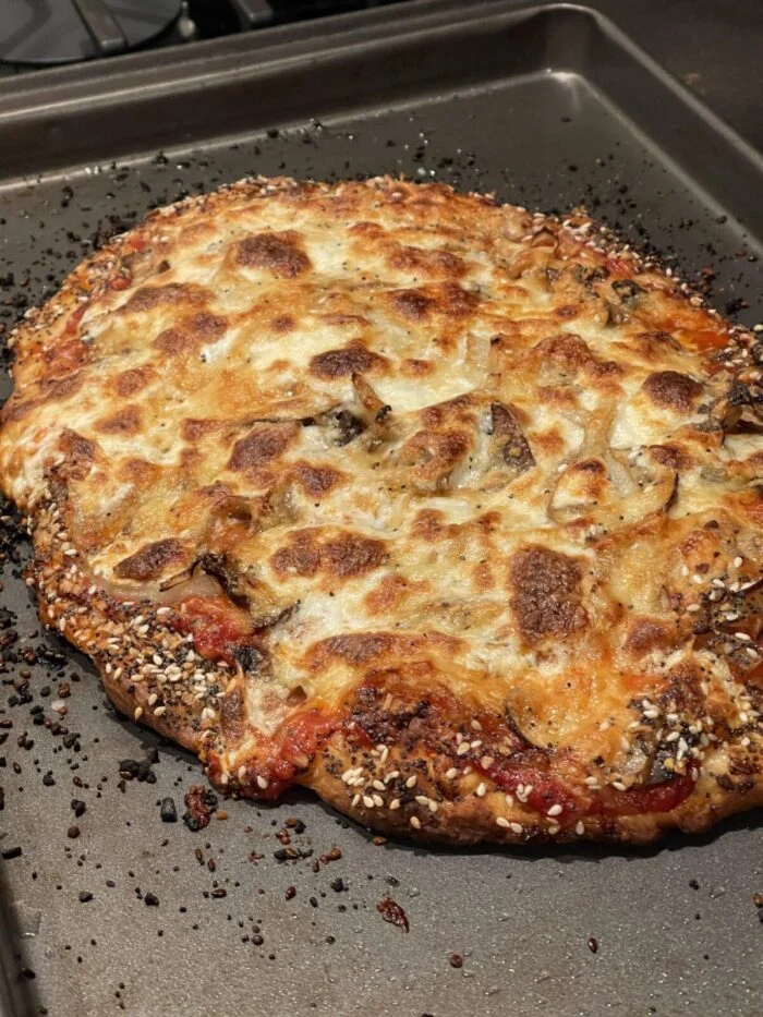 Blue Apron everything bagel crusted pizza on a baking sheet, browned cheese and seeded crust