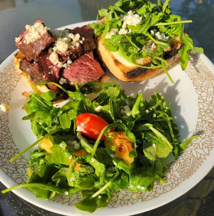 Blue Apron grilled steak and blue cheese open sandwiches with arugula, arugula salad with tomato and grilled peach on a plate