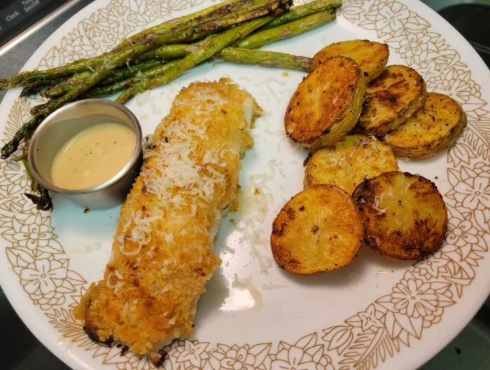 Blue Apron panko and parmesan crusted cod with a cup of ponzu mayo, roasted asparagus and potato rounds on a plate