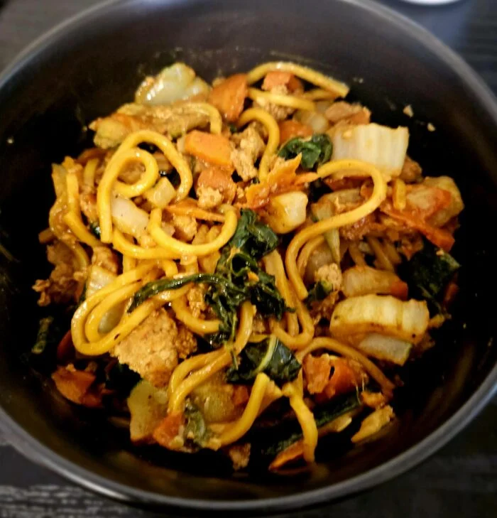 Blue Apron pork lo mein with ground pork, napa cabbage, carrots and leafy greens in a black bowl