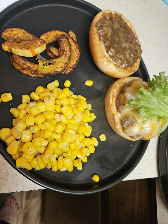 Blue Apron cheeseburger with caramelized onions, cheddar and lettuce on an open bun, roasted delicata squash and corn