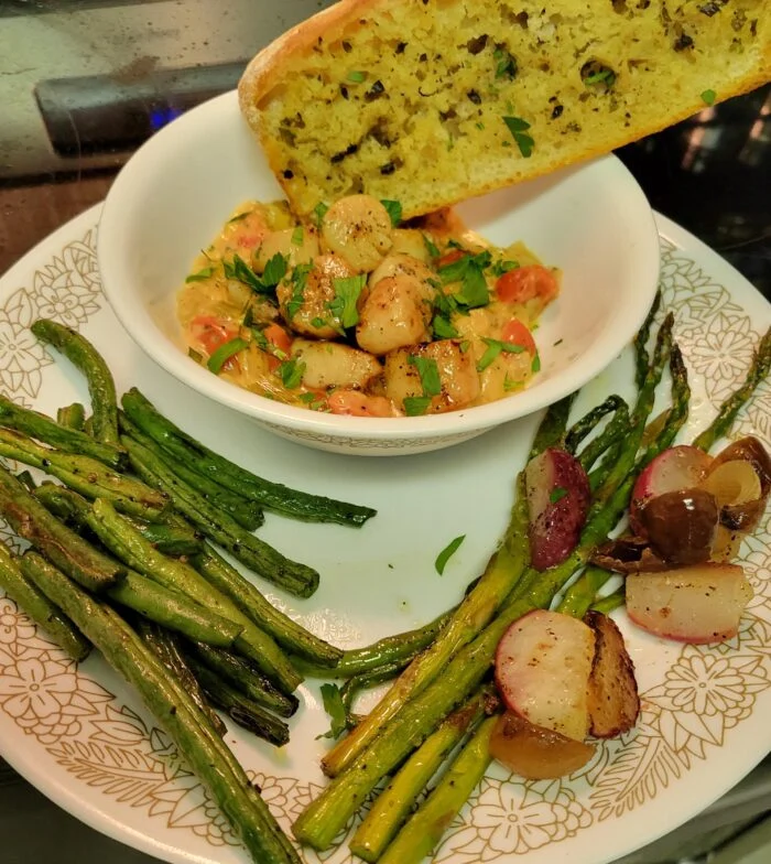 Blue Apron seared scallops in creamy tomato sauce in a bowl, with garlic herb bread, asparagus, green beans and radishes