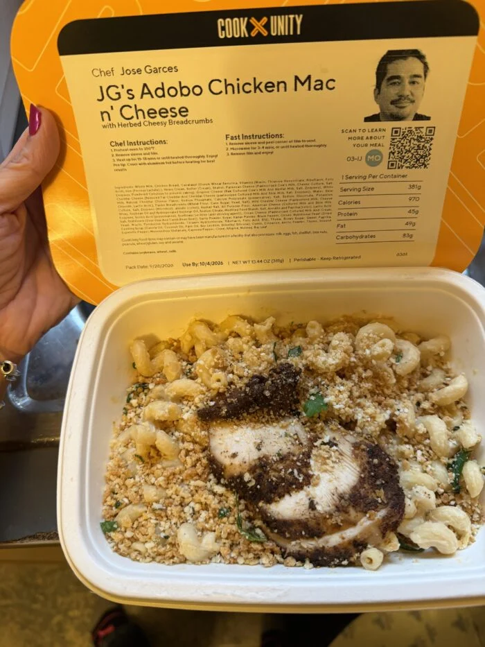 CookUnity adobo chicken mac and cheese topped with breadcrumbs in the tray, chef label held open above it