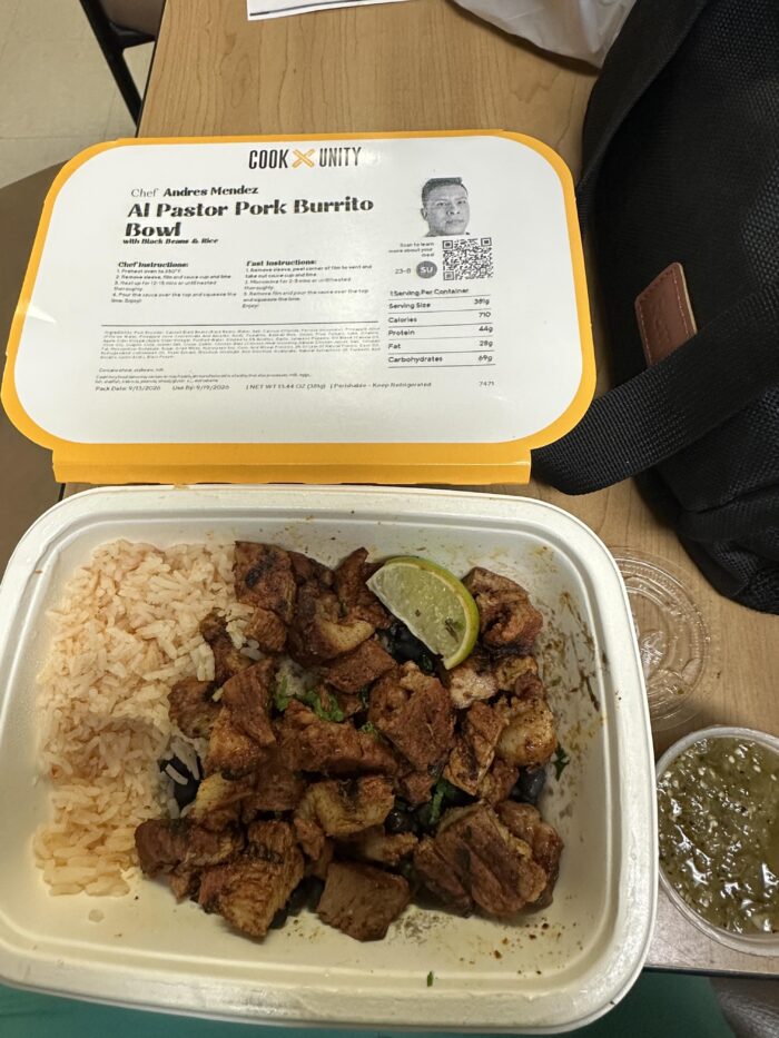 CookUnity al pastor pork burrito bowl, charred pork pieces with a lime wedge beside red rice, a green salsa cup and the chef label