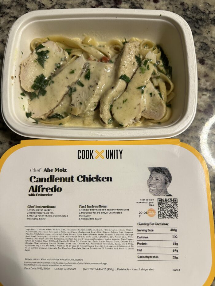 CookUnity candlenut chicken alfredo, sliced chicken over fettuccine in a cream sauce with parsley, chef label below the tray
