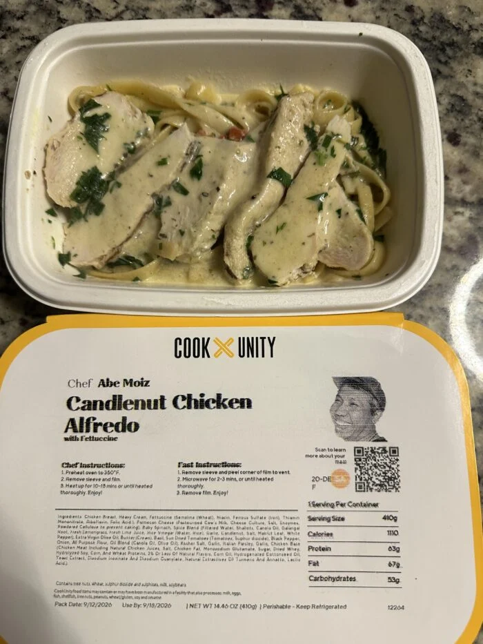 CookUnity candlenut chicken alfredo, sliced chicken over fettuccine in a cream sauce with parsley, chef label below the tray