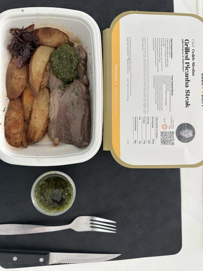 CookUnity sliced picanha steak with roasted potatoes, pickled red onion and chimichurri in the tray, extra chimichurri cup