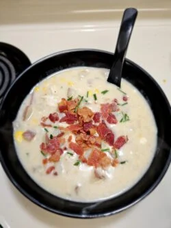 Bowl of Marley Spoon corn, bacon and chicken chowder topped with crumbled bacon and chives, spoon in the bowl