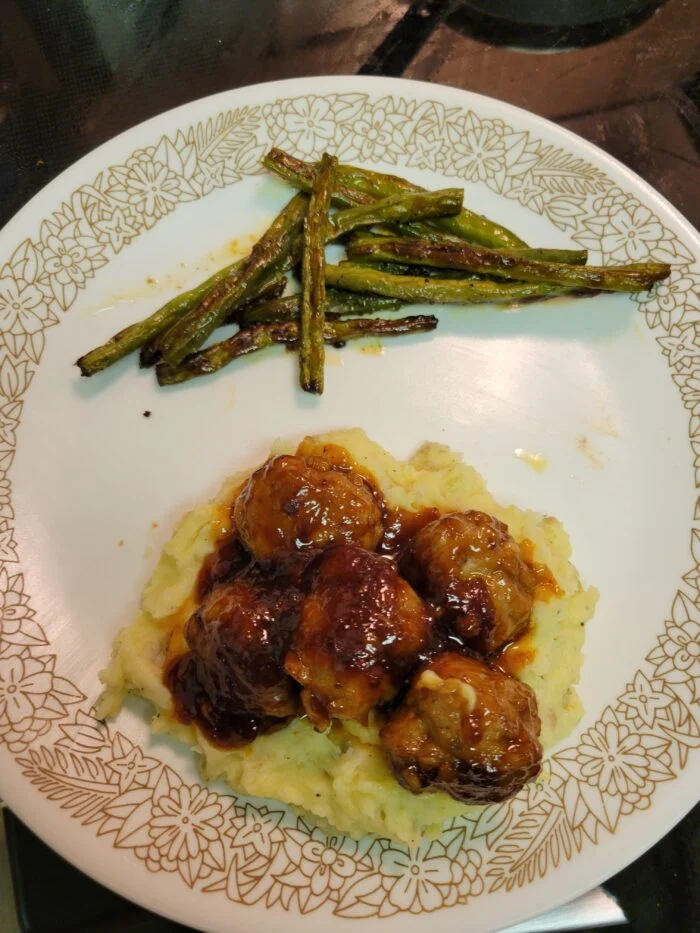 EveryPlate cherry glazed pork meatballs over mashed potatoes with roasted green beans on a white plate