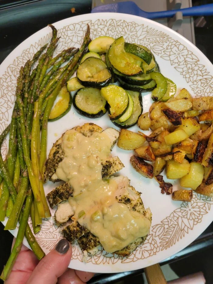 EveryPlate creamy Dijon chicken, sliced with sauce, with roasted potatoes, zucchini and asparagus on a plate