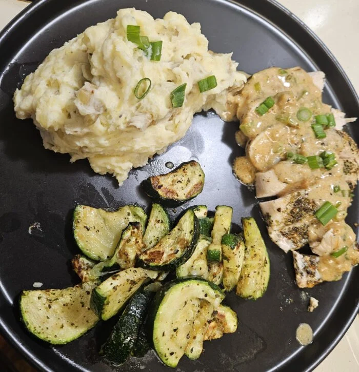 EveryPlate creamy Dijon chicken, sliced with sauce and scallions, roasted zucchini and mashed potatoes on a plate