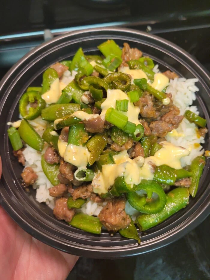 EveryPlate ponzu chili steak bowl with snap peas, sliced chiles, scallions and creamy sauce over rice in a black bowl