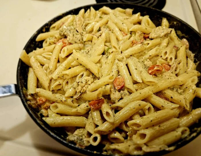 Green Chef chicken pesto penne with cherry tomatoes in a creamy sauce in a black skillet