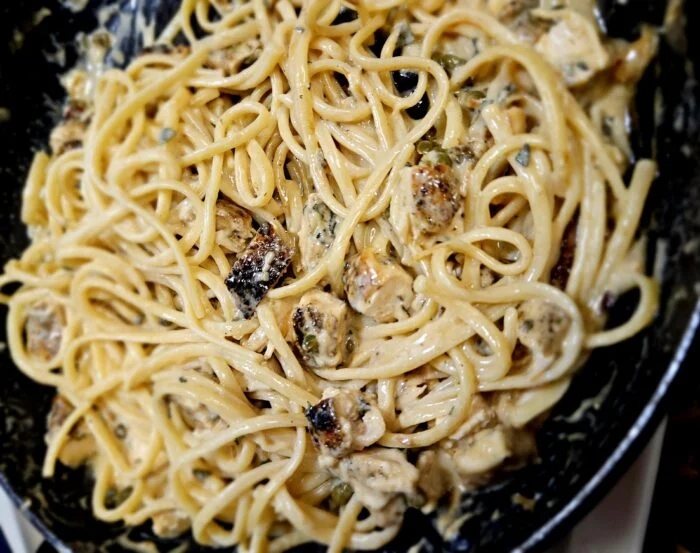 Green Chef chicken piccata with linguine, chicken pieces and capers in a creamy sauce in a dark skillet