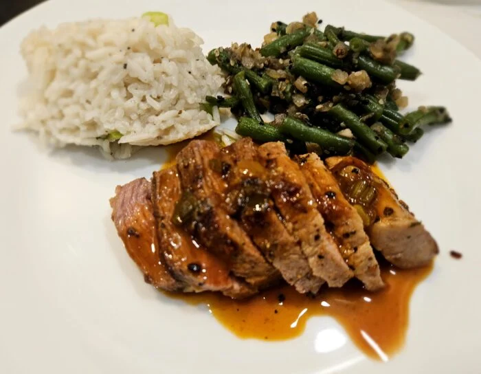 Green Chef sliced pork fillet with apricot sauce, jasmine rice and green beans on a white plate