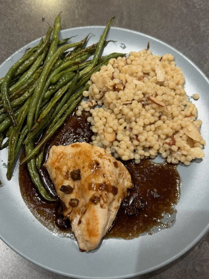 HelloFresh chicken in cherry balsamic sauce with green beans and pearl couscous with almonds on a grey plate