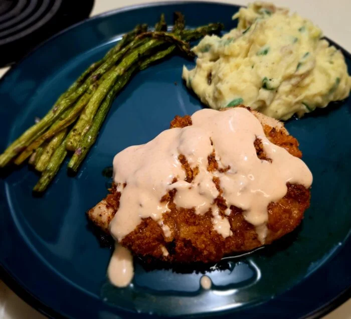 HelloFresh crispy cayenne chicken with creamy sauce, mashed potatoes and roasted asparagus on a teal plate