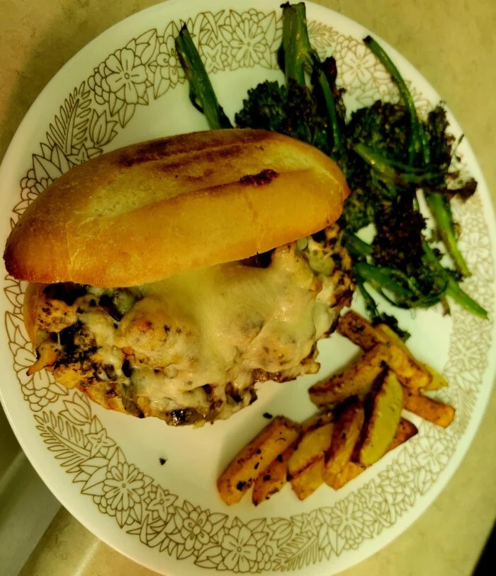 HelloFresh Italian chicken sandwich with melted cheese on a toasted roll with potato wedges and broccolini on a plate