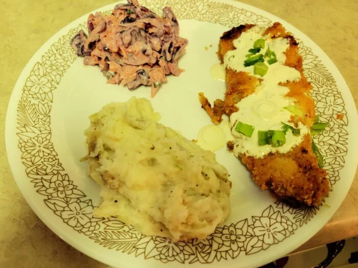 HelloFresh Louisiana style tilapia, breaded with creamy sauce and scallions, with cabbage slaw and mashed potatoes on a plate