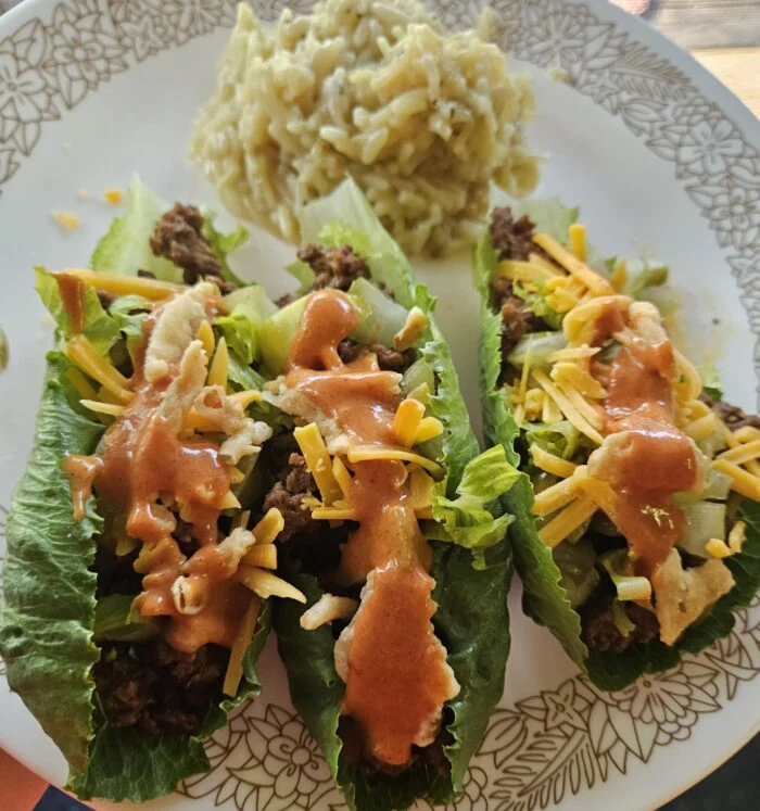 HelloFresh cheeseburger lettuce wraps with ground beef, shredded cheddar and sauce, with a side of creamy rice on a plate