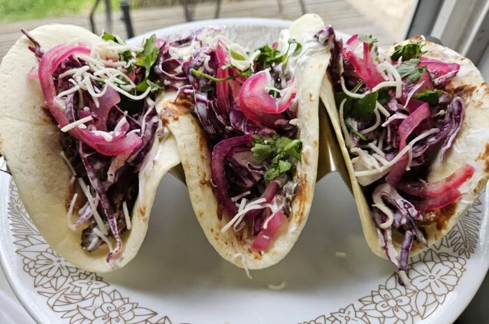 HelloFresh smashed black bean tacos with purple slaw, pickled red onion, cheese and cilantro on a patterned plate