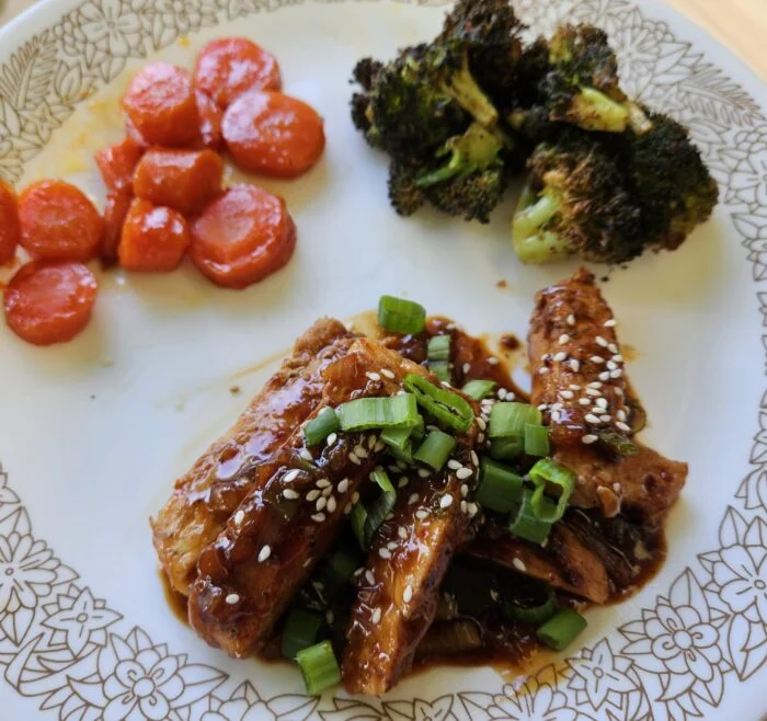 HelloFresh sweet soy glazed pork with sesame seeds and scallions, roasted carrots and broccoli on a patterned plate