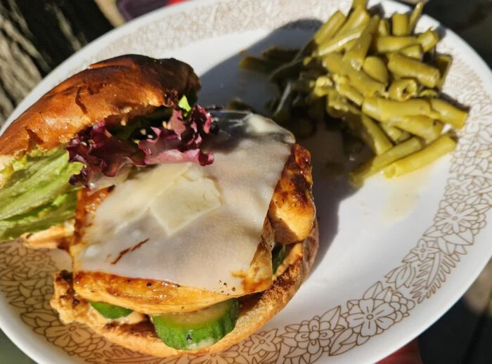 HelloFresh ponzu glazed chicken sandwich with melted cheese, cucumber and lettuce on a bun, with green beans on a plate