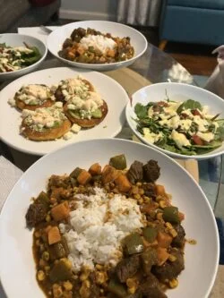 HelloFresh steak and sweet potato sancocho over white rice, with arepas and a spinach salad on separate plates