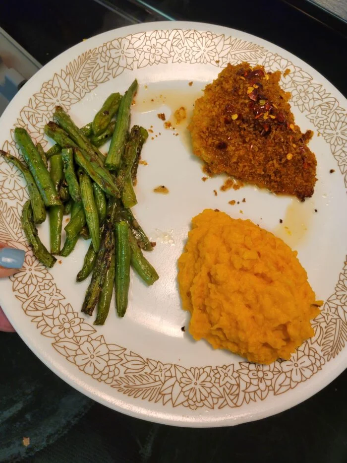 HelloFresh spicy maple chicken with crumb crust and chili flakes, mashed sweet potatoes and roasted green beans on a plate