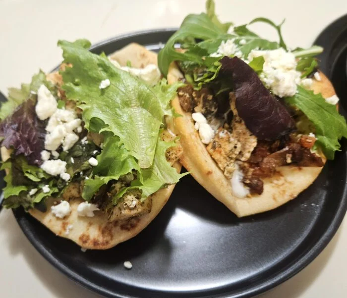 Home Chef chicken and feta gyros on flatbread with mixed greens and crumbled feta on a black plate