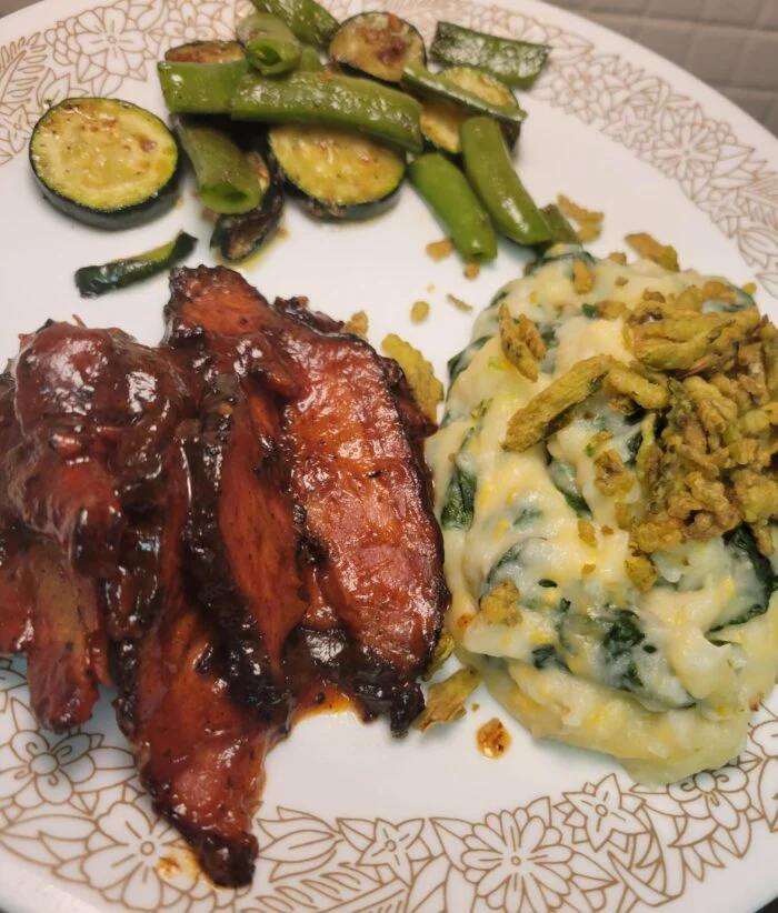 Home Chef glazed brisket slices with spinach mashed potatoes, crispy onions, zucchini and snap peas on a floral plate