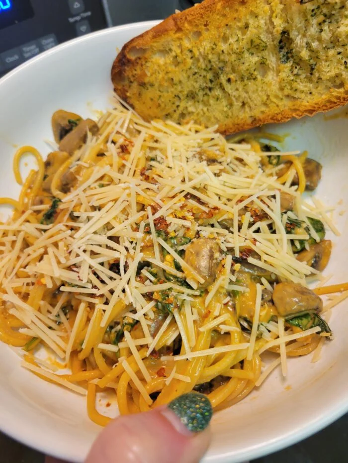 Home Chef mushroom Bolognese spaghetti with spinach, shredded parmesan, chili flakes and garlic toast in a bowl
