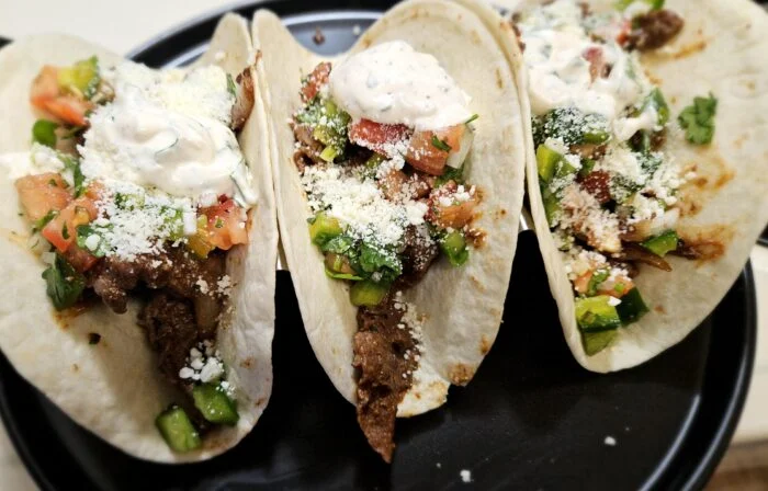 Home Chef barbacoa steak tacos with crumbled queso fresco, crema, tomato and green pepper on flour tortillas