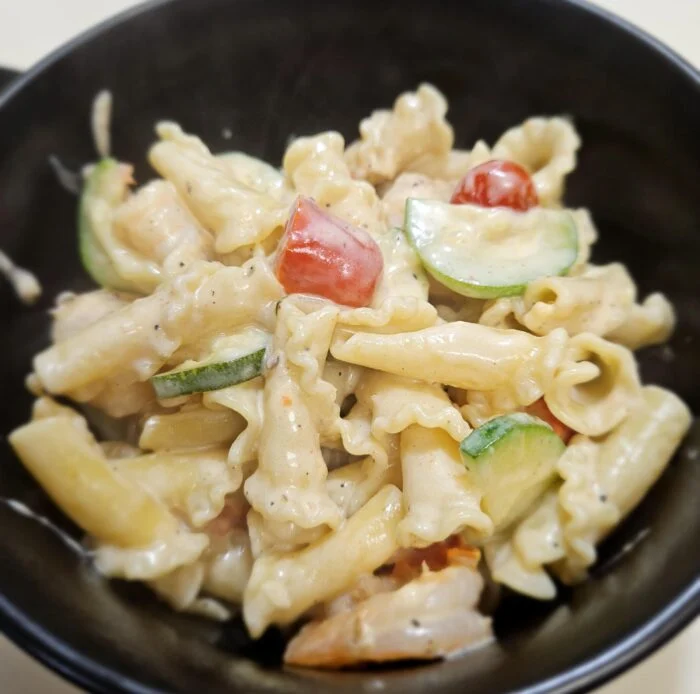Home Chef shrimp campanelle primavera with zucchini and tomato in a creamy parmesan sauce in a black bowl