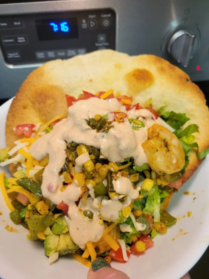 Home Chef shrimp taco bowl in a crisp tortilla shell with lettuce, corn, peppers, tomato, avocado, cheese and creamy sauce
