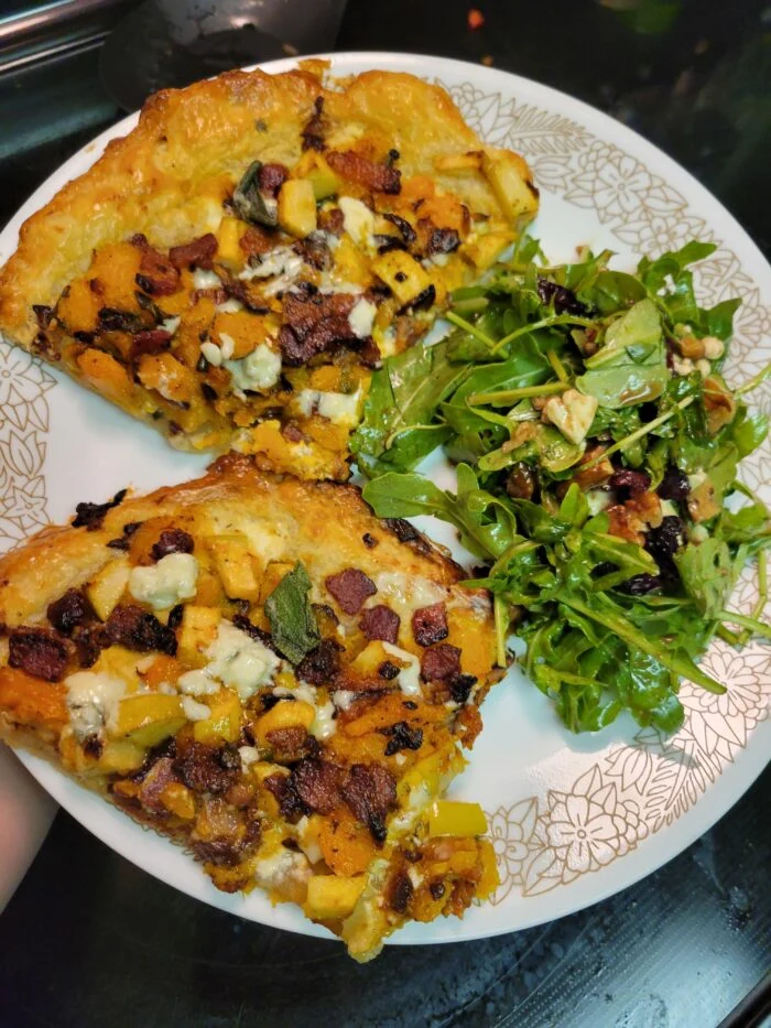 Marley Spoon butternut squash, bacon and apple galette slices with blue cheese and sage beside an arugula salad