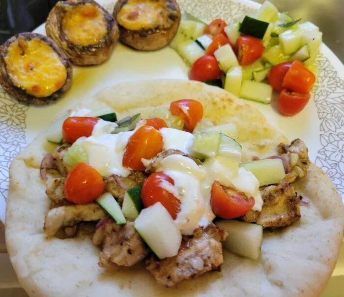 Marley Spoon Greek chicken gyro on pita with tomato, cucumber and garlic sauce, chopped salad and stuffed mushrooms