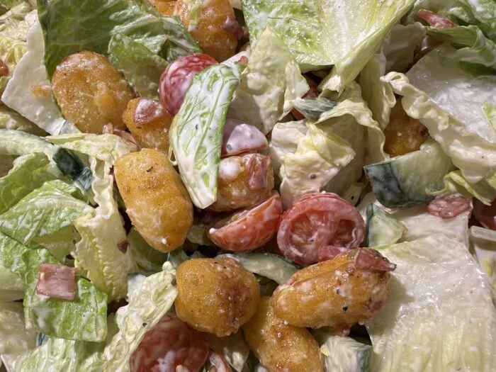 HelloFresh crispy gnocchi and bacon Caesar salad, close up, with romaine, halved cherry tomatoes and creamy dressing