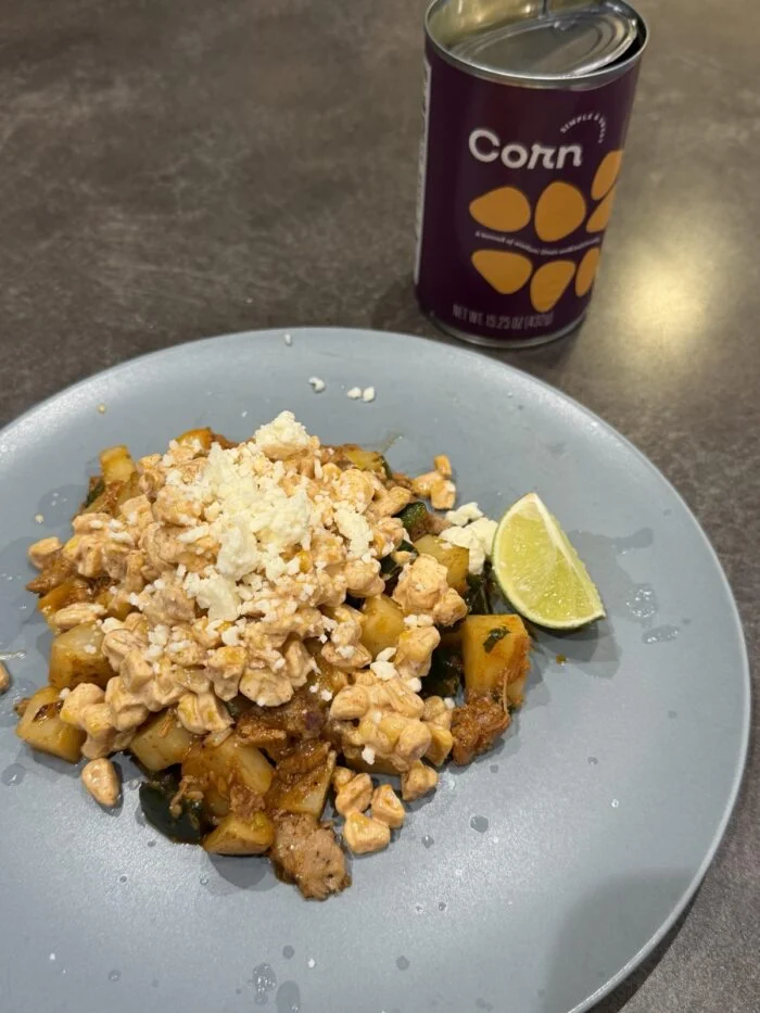 HelloFresh Mexican street corn pulled pork hash on a pale plate with a lime wedge and chopped coriander