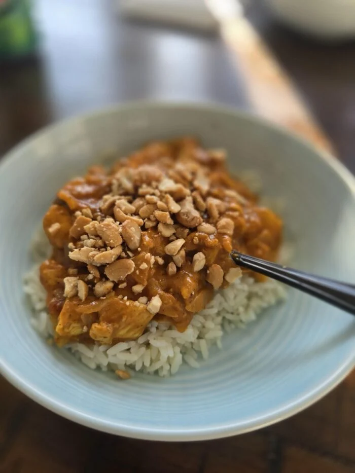 Home Chef butter chicken served over white rice in a pale blue bowl, topped with chopped peanuts
