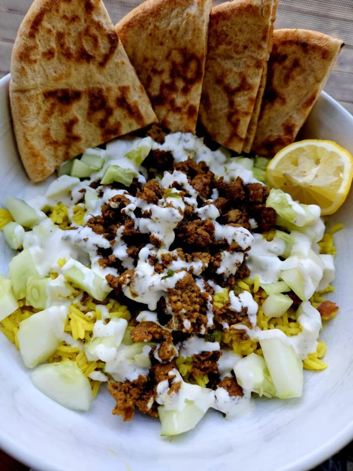 HelloFresh street cart style turkey bowl with yellow rice, cucumber, white sauce, pita wedges and a lemon half