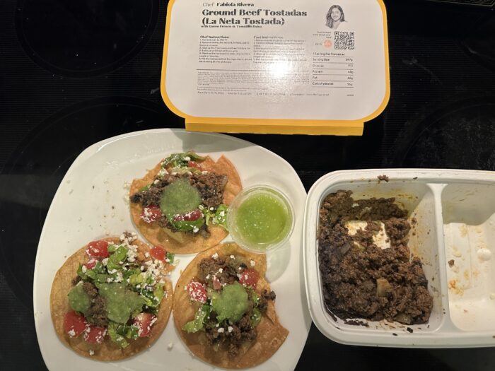 CookUnity ground beef tostadas, three plated with guacamole, tomato and a green salsa cup, beside the tray and chef label