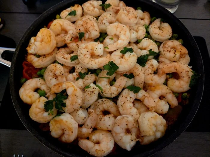 Marley Spoon shrimp and chorizo paella in a skillet, seasoned shrimp over rice with peas and parsley